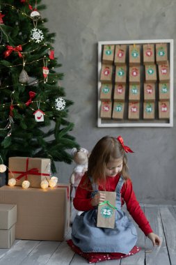 Noel gelenekleri konsepti, el yapımı Noel takvimi olan çocuk, içinde 25 numara şekerlemeler olan kız, el yapımı el yapımı hediyeler.