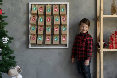 El yapımı Noel takvimine yakın bir çocuk, Noel arifesinde duvarda asılı duran şeker paketleri, Noel çocukları hayran konsepti.