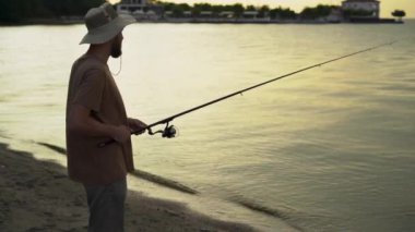 ,bearded man fisherman at dawn on the lake catches fish with a bait. stands and waits for a bite. Fishing holiday concept. copy space