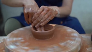 Usta çömlekçi kadın eski bir çömlekçinin çarkında kilden bir sürahi yaratıyor, ayağını büküyor. Yüzü olmadan yakın plan.