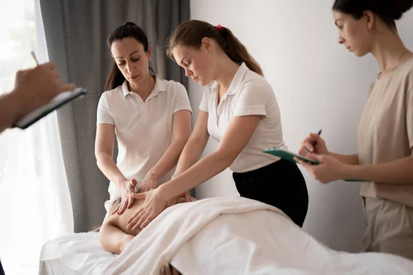 Woman teacher helping students become a masseuse, wellness massage training concept