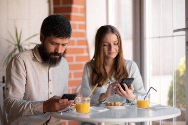 Couple having fun using smartphone at breakfast time, good morning and technology concept
