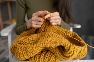 Closeup of knitting hands, knits woolen clothes, Woman knits sweater, hands out of focus.