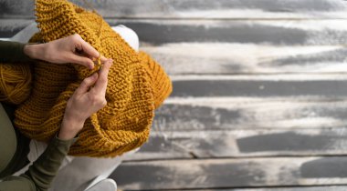 Close-up of hands knitting, Woman knits sweater. Focus on knitted fabric, hands out of focus. Top view. banner, place for your advertising