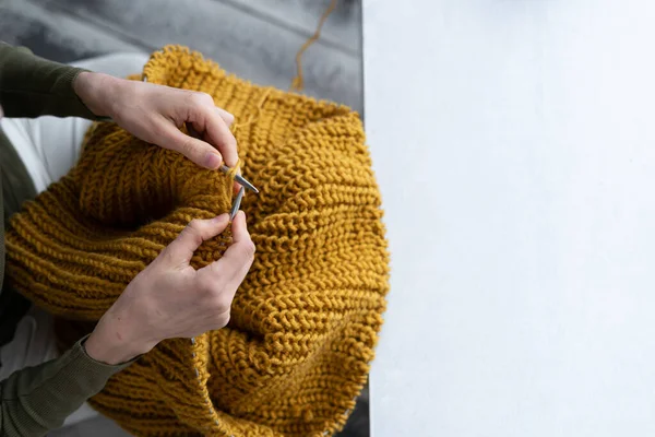 Close-up of female hands knitting wool sweater. Woman knits from thick yarn. Handmade clothes. The girl goes in for her hobbies. Knitting concept