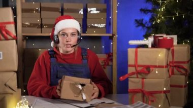 small business owner caucasian female freelancer santa works at home office, holding crumpled and broken box in hands, informing customers about product damage. webcam view. Christmas sale concept