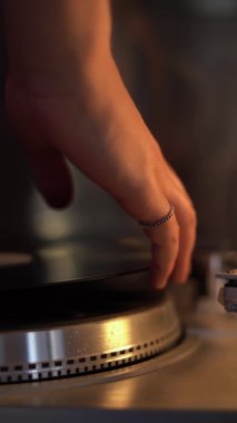 close-up of male hands put a vinyl record on the player and turn on the music. vertical video. Needle on a plate