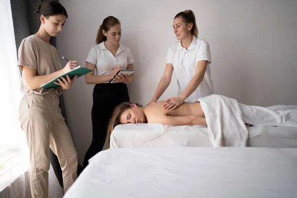 Massage training concept. Teacher helps students become masseuses. Wellness massage masseur training