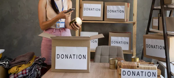 Volunteer hands collecting food into donation box. Working at food bank concept. image of hands packing cans at food drive. Donate food. Volunteers office