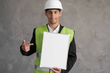 Arabic Man engineer wearing a hard hat pointing at an empty clipboard