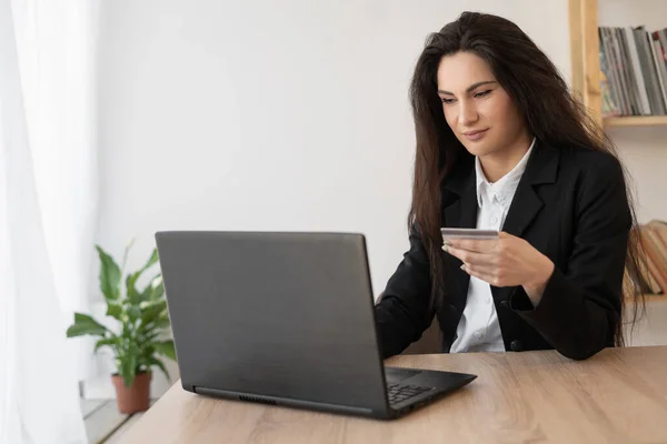 Businesswoman doing online shopping through laptop and credit card sitting in the office. online shopping concept