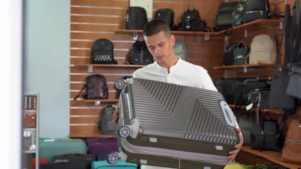 Young Caucasian Man Stands Suitcase Store Chooses Bag His Hand — 비디오