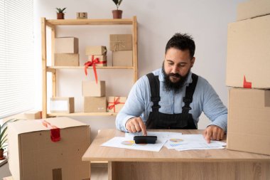 Genç Hintli girişimci küçük işletme KOBİ serbest hesap makinesini kullanarak sipariş istemcisini hesaplar ve sipariş siparişi hazırlama paketini kontrol eder..