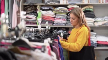 Portrait of a woman choosing clothes in a store. standing near a showcase with womens clothing chooses a vest from the autumn or spring collection. The concept of shopping and consumerism.