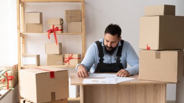 Çalıştır. Genç Hintli adam klip tahtası ve teslimat kutusu olan müşteriden yeni bir sipariş alıyor. Ev ofisinde çalışan küçük bir işletme sahibi, KME, online alışveriş kavramı.