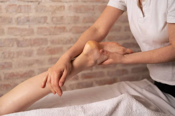 Leg massage treatment in the spa salon, a woman receiving a holistic massage treatment. Physiotherapist massaging her patients foot in medical office