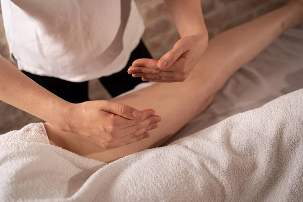 masseur makes anti-cellulite massage on the legs and thighs of patient. Treatment of excess weight. massage young woman in spa salon. Close up