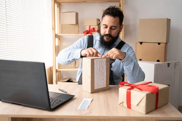 a man sticking a barcode on a cargo on his desk. A person working in a dropshipping office prepares a package for delivery to a customer. SME concept