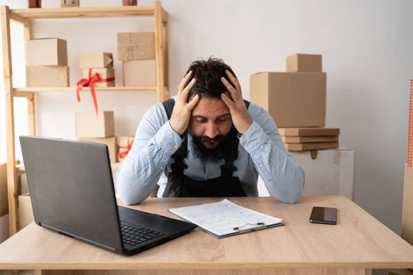 Frustrated business man looking at laptop holding his hands to his head in frustration. portrait of tired sick upset young indian man with strong migraine