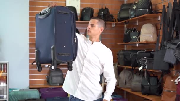 Young Caucasian Man Shirt Chooses Travel Suitcase Supermarket Comparing Fabric — Vídeo de Stock