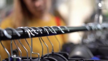 Close-up of a hanger on a showcase in a womens clothing store. a lady sorts through clothes in a boutique and chooses to buy from a new collection. The concept of shopping and consumerism.