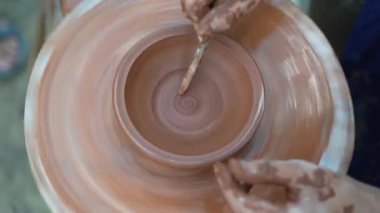 Pottery workshop and workshop female professional potter works and makes pottery in pottery workshop draws a pattern on a bowl. Handmade, education and study concept