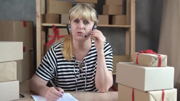 Elderly Woman Online Store Consultant Works Using Headphones Small Delivery — Stock videók