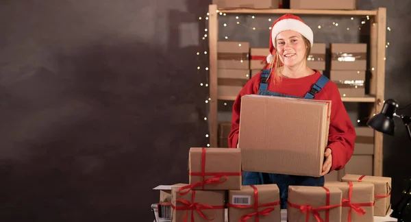 Young Woman Wearing Santa Claus Hat Works Warehouse Boxes Gifts — Stok fotoğraf