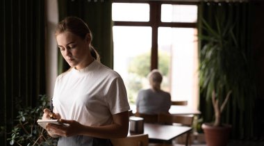Young waitress small cafe business owner wear apron uniform holding notepad pen write notes take order in restaurant, waiting staff, hospitality, good customer service concept