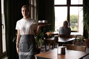 girl waitress carries a cup on a tray at cafe. Selective focus. Copy space