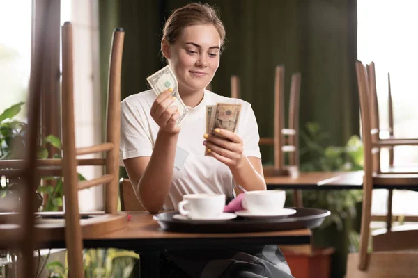 Leave tipping for the waiter in cafe. salary or tips, counting embracing money with satisfaction on face. waitress while count money in a cafe.