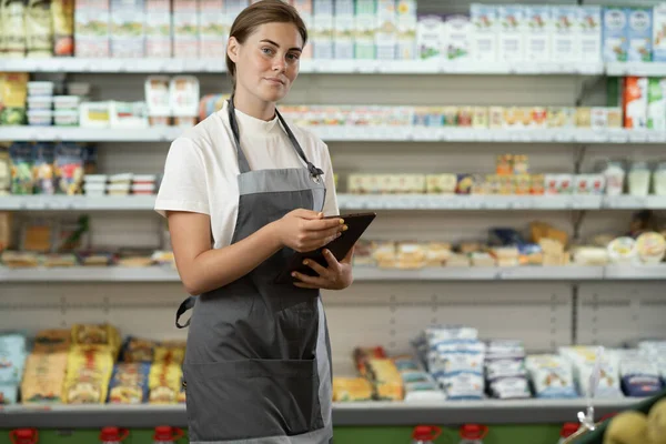 Süpermarketin dijital tablet kullanan gülümseyen personelin portresi.