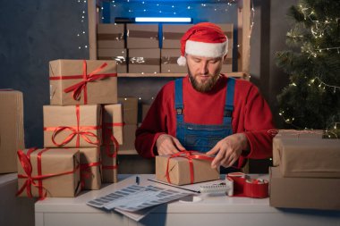 man entrepreneur small business owner is packing goods at home in a small office. Prepares boxes for shipment. Big sale for Christmas. home office is seller of online store. start-up. copy space
