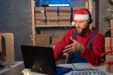 Small business aspiring entrepreneur Santa Claus, SME freelance working in home office using computer, online marketing packaging box delivery on Christmas, e-commerce holiday telemarketing concept.