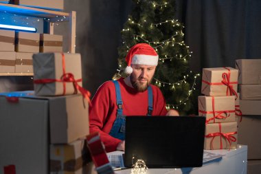 man entrepreneur small business owner working at home in a small office. Prepares orders boxes for shipment. Big sale for Christmas. The home office is the seller of the online store. start-up