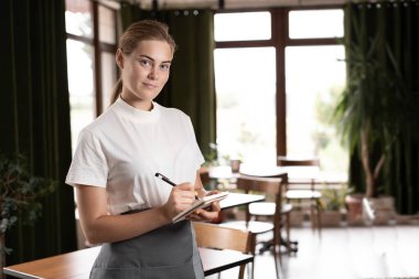 Young waitress small cafe business owner wear apron uniform holding notepad pen write notes take order in restaurant, waiting staff, hospitality, good customer service concept