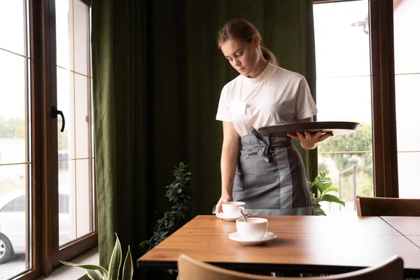 Waitress holding tray take empty cup from coffee, female hands serving hot aromatic brewed coffee drinks at cafe table, coffee house shop service concept