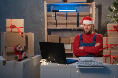 Small business aspiring entrepreneur, SME freelance worker working in a home office man in Santa Claus hat and accepts an online order using an application and a laptop, Christmas sale concept