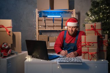 Small business aspiring entrepreneur Santa Claus, SME freelance working in home office using computer, online marketing packaging box delivery on Christmas, e-commerce holiday telemarketing concept.