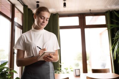 Waitress writing an order into a notebook working at cafe. copy space