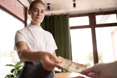 Waitress takes the tip. The waiter female receives a tip from the client at the cafe or restaurant. Service concept