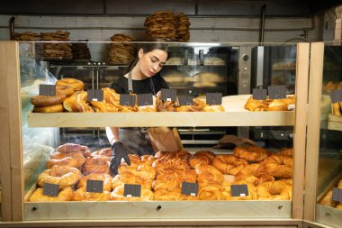cheerful woman working at her bakery smiling standing near the showcase with delicious desserts, entrepreneur profession positivity small business owner, copy space