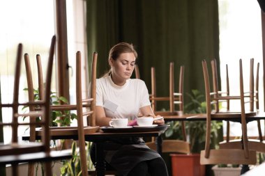 Waiter resting in a cafe at the table, tired restaurant worker, hospitality service concept