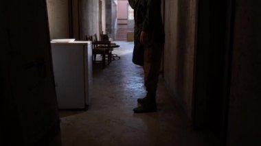 A male researcher in a gas mask with a flashlight inside the corridor of an old ruined room, finds canned food in an old refrigerator. The concept of post-apocalyptic world. Looking for food
