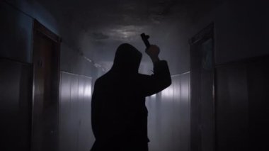 Man in respirator gas mask, hood and camo pants walk on the inside of abandoned building with flashlight. Cyberpunk postapocalypse fantasy horror scene or air pollution