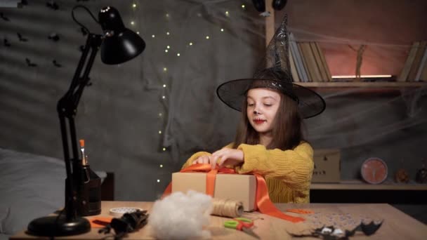 Απόκριες Χαριτωμένο Μικρό Μάγισσα Ανοίγοντας Ένα Κουτί Κάθεται Στο Τραπέζι — Αρχείο Βίντεο