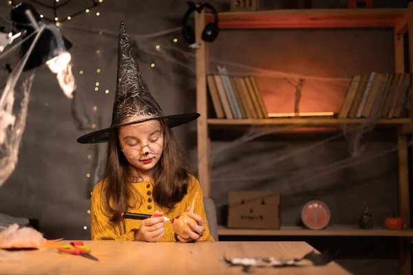 Милая Счастливая Маленькая Ведьма Готовящаяся Хэллоуину Рисующая Страшное Лицо Тыкве — стоковое фото