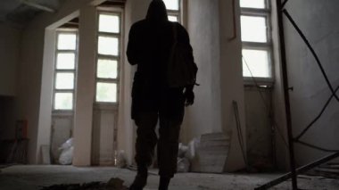 Gaz maskeli ve sırt çantalı bir adam terk edilmiş büyük bir binanın içinden geçiyor. Kıyamet sonrası dünyada yiyecek arayışında hayatta kalan birinin konsepti. Boşluğu kopyala.