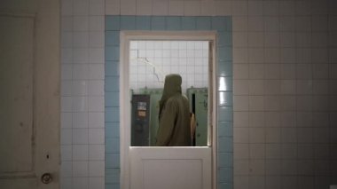 Bandajlı ve kapüşonlu bir adam yıkılmış bir binanın etrafında yürüyor. Nükleer kimyasal savaştan sonra hayatta kalan bir takipçi konsepti..
