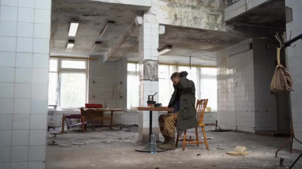 Homem Senta Mesa Num Edifício Abandonado Pós Apocalipse Sobrevivente Humano — Vídeo de Stock